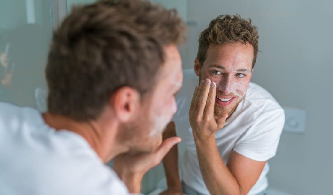 Young man washing face with facial cleanser
