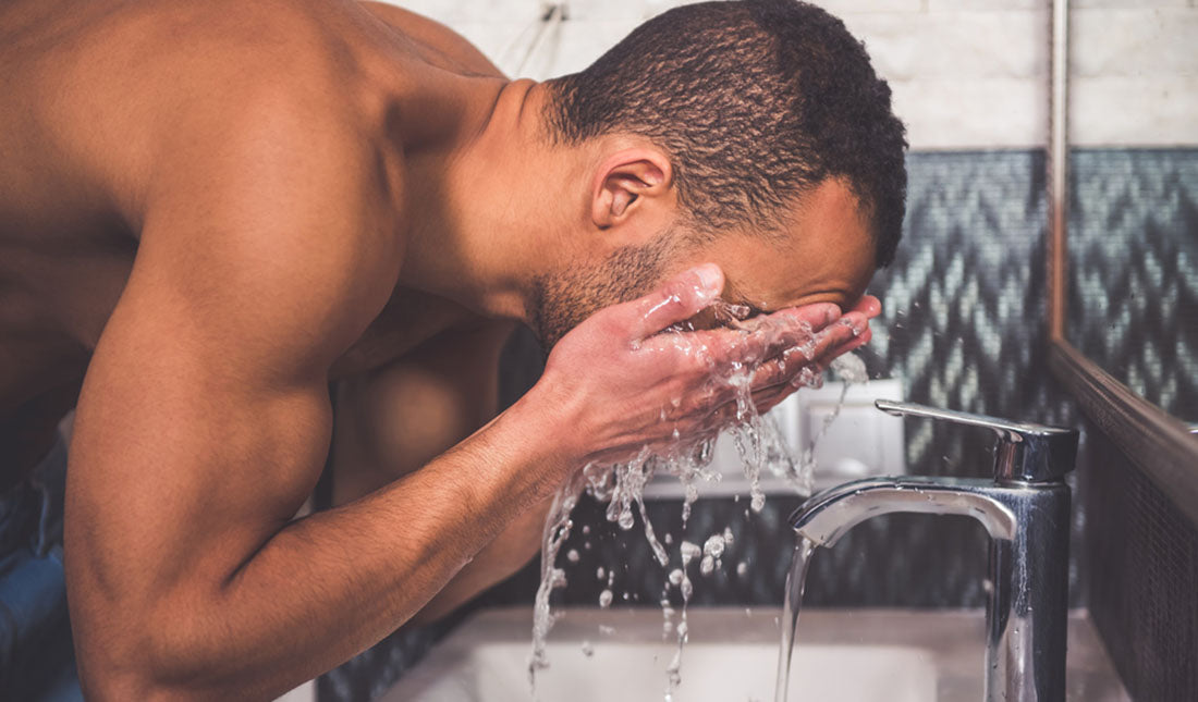 Man washes face at bathroom sink